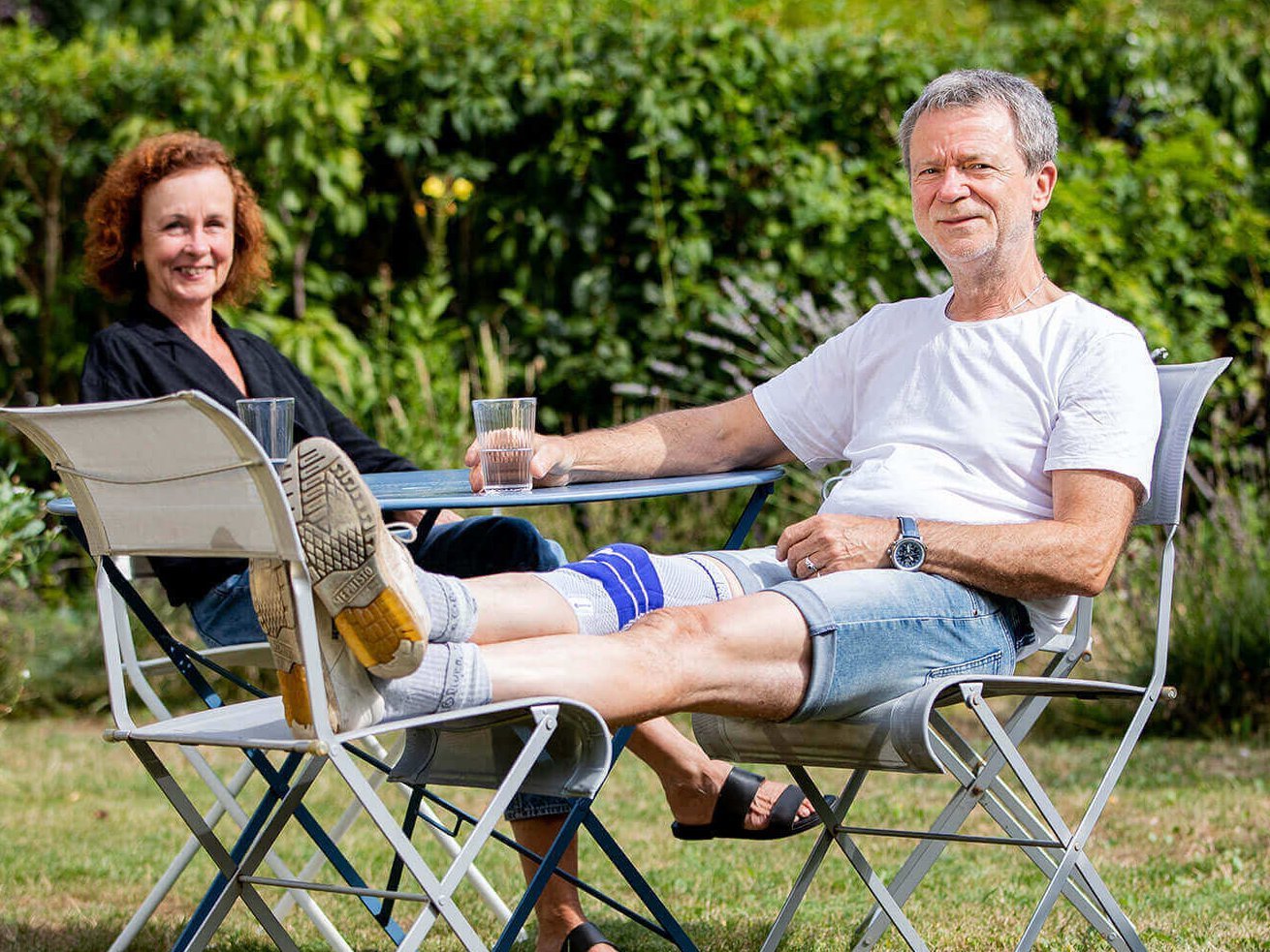 Dieter und seine Frau genießen den Sommer im Garten Dieter und Ulli sitzen an einem Tisch in ihrem gepflegten Garten. Dieter trägt eine GenuTrain Kniebandage von Bauerfeind.